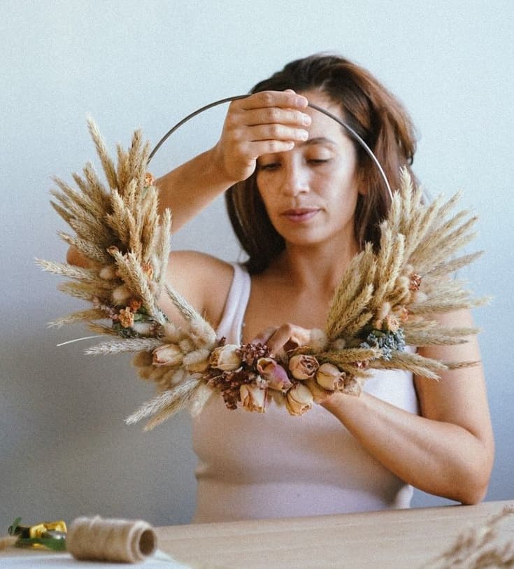 Daniela holding a dried wreath of wheat, pampas and seed heads