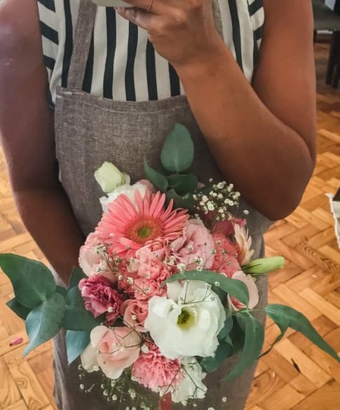 Fresh seasonal bouquet of gerbera, roses and lisianthus held in an apron