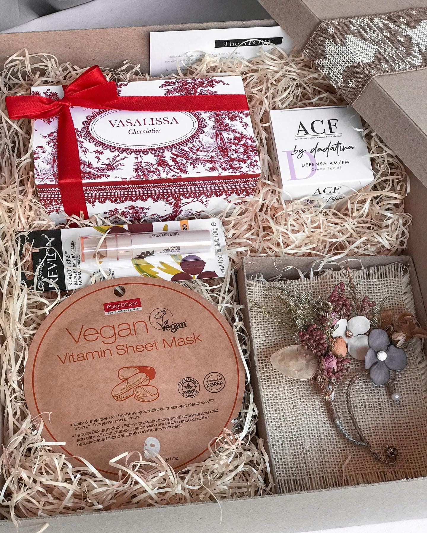 Open gift box with curated products, dried florals and wood wool