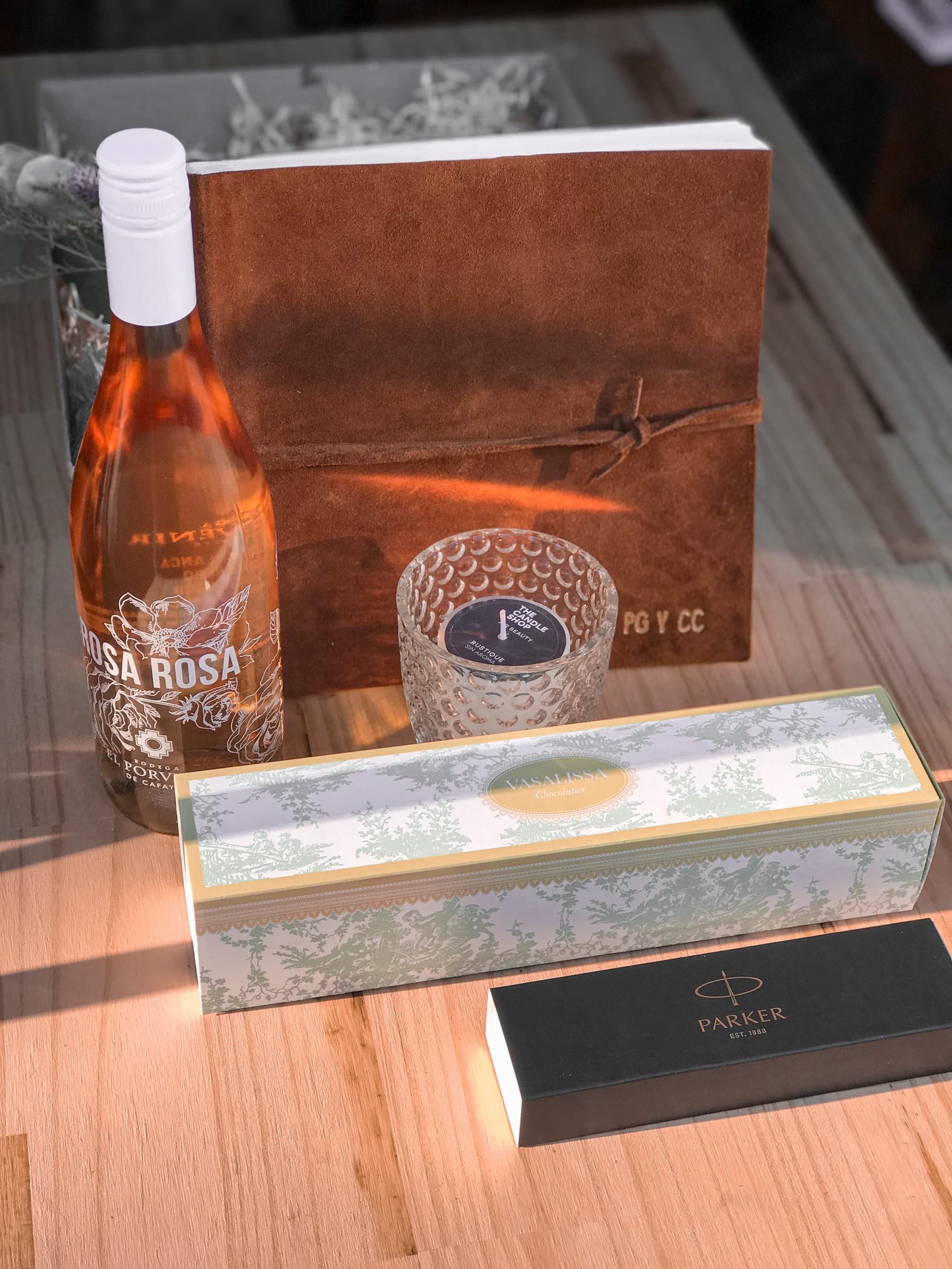 Gift box experience with rosé, a candle and a notebook laid out on a table