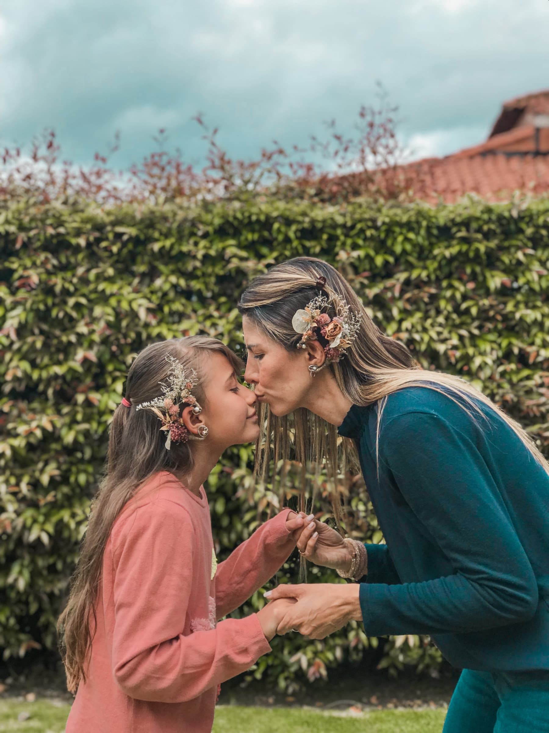 Two guests wearing floral ear adornments at an outdoor celebration